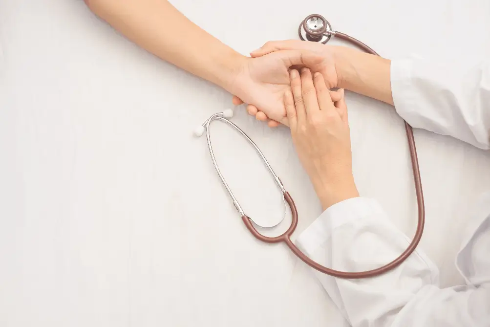 Close-up of a doctor in Athens, GA gently holding a patient's hand, symbolizing care and compassion in healthcare.